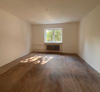 Ein geräumiges Zimmer in einem Einfamilienhaus mit einem Holzboden und einem großen Fenster.