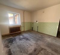 Ein Zimmer in einem Einfamilienhaus mit einem Fenster, einem Heizkörper und hellgrünen Fliesen.