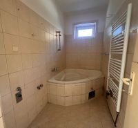 Ein Badezimmer in einem Einfamilienhaus mit einer Eckbadewanne und einem Heizkörper an der Wand.
