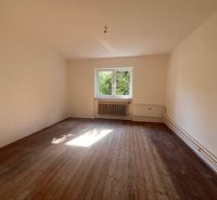 Innenraum eines Einfamilienhauses mit Holzboden und Fenster mit Blick ins Grüne.