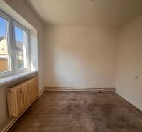 Ein Zimmer in einem Einfamilienhaus mit einem Fenster und einem Boden in Holzoptik.