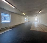 Innenfotografie zeigt einen leeren Raum mit schwarzem Boden und Fenstern, Lager und Hallen.
