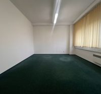 Büros mit Teppichboden und Vorhängen an großen Fenstern.