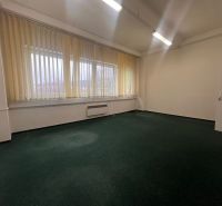 Büros mit dunklem Teppichboden und vertikalen Jalousien an großen Fenstern.