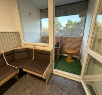 Helle Loggia einer 4-Zimmer-Wohnung mit Aussicht und Holzmöbeln.