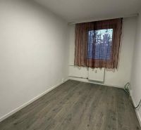 Ein Zimmer in einer 4-Zimmer-Wohnung mit einem Boden in Holzoptik und einem einfachen Vorhang.