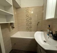 Badezimmer mit Badewanne in einer 4-Zimmer-Wohnung, mit Ablagefächern und dekorativen Fliesen.