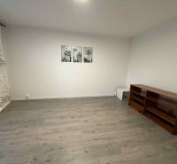 Wohnzimmer in einer 4-Zimmer-Wohnung mit Holzboden, Regal und Bildern an der Wand.
