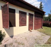 Ein Ferienhaus in Nové Zámky mit Holzläden und einem gepflegten Garten.