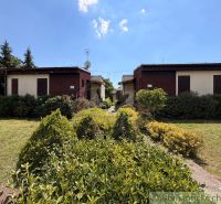 Ein Ferienhaus in Nové Zámky, umgeben von einem gepflegten Garten und Grünflächen, blauer Himmel.