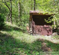 Eine Hütte zwischen den Bäumen in Slovenská Ľupča, umgeben von Grün und Blumen.