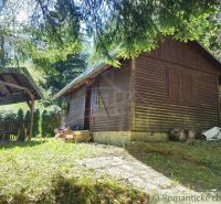 Eine Holzhütte in Slovenská Ľupča, umgeben von Grünflächen und einem Unterstand zum Sitzen.