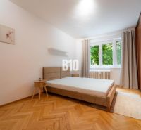 Schlafzimmer in einer 2-Zimmer-Wohnung mit großem Bett, Holzboden und Kleiderschrank.