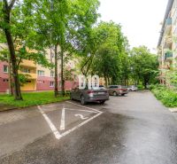 Ein Parkplatz mit Autos und Wohnhäusern, umgeben von Grünflächen in Martin.