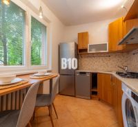 Küche in einer 2-Zimmer-Wohnung mit Holzelementen und Geräten, wunderschön beleuchtet.