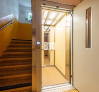 Das Treppenhaus eines Gebäudes mit einem offenen Aufzug und gelben Wänden in einem Wohnhaus.