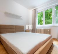 Schlafzimmer in einer 2-Zimmer-Wohnung mit großem Fenster und Boden in Holzoptik.
