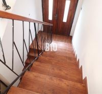 Eine Treppe in einem Einfamilienhaus mit einem Boden in Holzoptik und einem Geländer aus Metall.