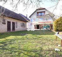 Ein Einfamilienhaus in Turany, umgeben von einem Garten mit einer Bank und Anbauten.