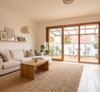Wohnzimmer in einem Einfamilienhaus mit bequemer Couch, Holztisch und Terrasse.
