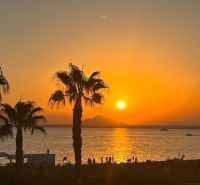 Sonnenuntergang mit Palmen und Meer in La Manga del Mar Menor, Spanien.