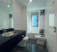 Badezimmer in einer Ferienwohnung mit Badewanne und Waschbecken auf einer dunklen Arbeitsplatte.