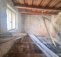 Ein Zimmer in einem Einfamilienhaus mit Steinwänden und einer Holzdecke, Material auf dem Boden.