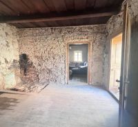Steinwände und Türen in einem Raum in einem Einfamilienhaus mit alten Möbeln.