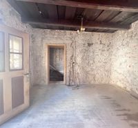 Rustikaler Raum in einem Einfamilienhaus mit Steinwänden und einem Boden in Holzoptik.