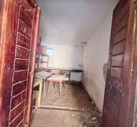Holztüren führen in einen Raum eines Einfamilienhauses mit Möbeln und rohem Boden.