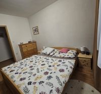 Schlafzimmer in einer 3-Zimmer-Wohnung mit Bett, Kommode und Boden in Holzoptik.