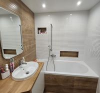 Badezimmer in einer 3-Zimmer-Wohnung mit Badewanne und Holzdekor.