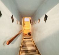 Ein enger Treppenaufgang mit Wänden, die mit Bildern in einer 3-Zimmer-Wohnung dekoriert sind.