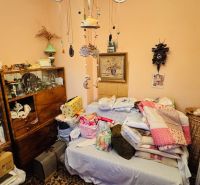 Ein Zimmer in einer 3-Zimmer-Wohnung mit einem Bett, Decken und einem Bücherregal mit Büchern.