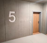 Betonwand mit der Nummer fünf und Holztüren in einer Zweizimmerwohnung.