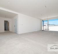 Ein leerer Raum in einer 3-Zimmer-Wohnung mit einem großen Fenster und einer Terrasse.
