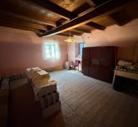 Ein Zimmer in einem Einfamilienhaus mit Möbeln, Ziegelstapeln und einer Holzdecke.