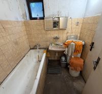Ein Badezimmer in einem Einfamilienhaus mit einer Badewanne, einem Waschbecken und beigefarbenen Fliesen an den Wänden.