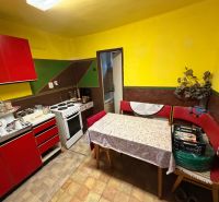 Eine Küche in einem Einfamilienhaus mit roten Möbeln, einem Tisch und einem Elektroherd.