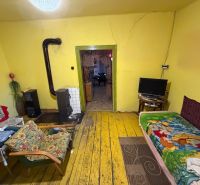 Ein Zimmer in einem Einfamilienhaus mit einem Ofen, gelben Wänden und einem Boden in Holzoptik.