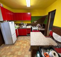 Einfamilienhaus mit Küche, roten Schränken und weißen Geräten.