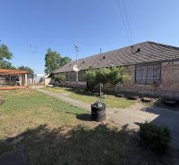 Ein Einfamilienhaus in Nesvady mit einer ungepflegten Fassade, einer Holzpergola und einem gepflegten Garten.