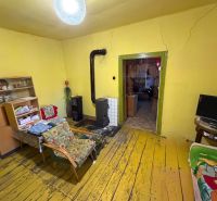 Wohnzimmer in einem Einfamilienhaus mit Ofen, gelben Wänden und einem Boden mit Holzdekor.