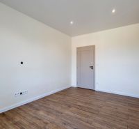 Ein leerer Raum mit einem Holzboden und hellen Wänden in einem Einfamilienhaus.