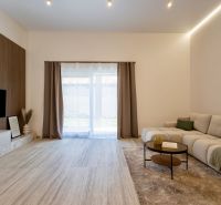 Wohnzimmer eines Einfamilienhauses mit Sofa, Holzboden und Fernseher an der Wand.
