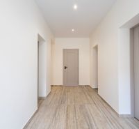 Ein Flur in einem Einfamilienhaus mit einem Boden in Holzoptik und weißen Wänden.