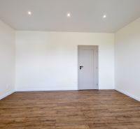 Ein Raum mit einem Holzboden und weißen Wänden in einem Einfamilienhaus.