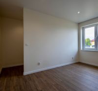 Ein Zimmer in einem Einfamilienhaus mit einem Holzboden und einem großen Fenster.
