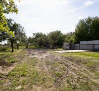 Ein Grundstück in Zemplínska Široká mit Gras, Bäumen und einem Blechzaun neben einem Einfamilienhaus.