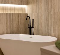 Freistehende Badewanne mit modernem schwarzen Wasserhahn in einem Einfamilienhaus.